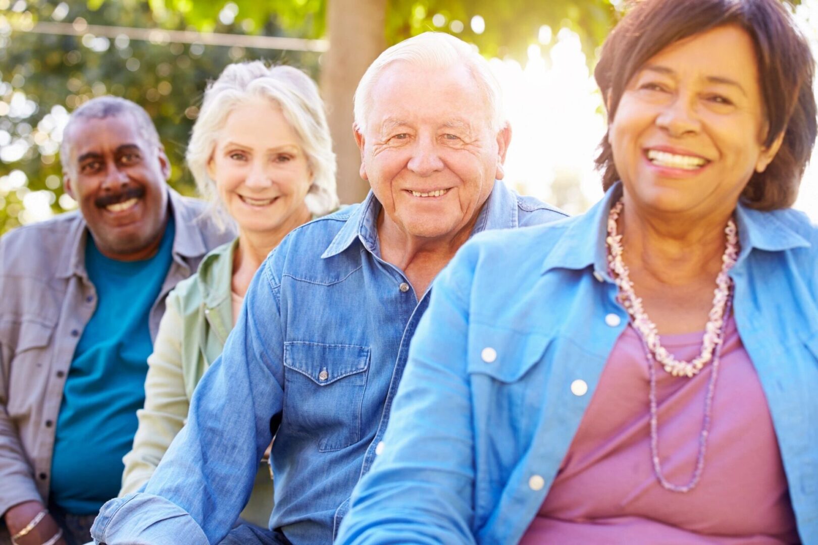 A group of diverse seniors smiling outdoors together.